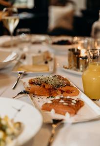 une table avec des plaques alimentaires et un verre de jus d'orange dans l'établissement Cobergher Hotel, à Courtrai