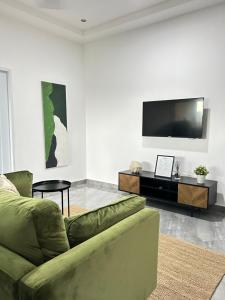 a living room with a green couch and a flat screen tv at 2-Bedroom Flat by PanAfri Homes in Accra