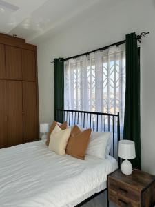 a bedroom with a bed with green curtains and a window at 2-Bedroom Flat by PanAfri Homes in Accra