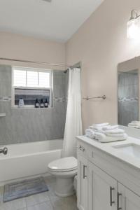 Baño blanco con aseo y lavamanos en The Gator Grove Retreat, en Gainesville