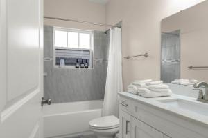a white bathroom with a toilet and a sink at The Gator Grove Retreat in Gainesville +24 photos