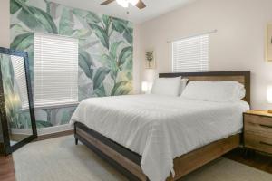 1 dormitorio con 1 cama grande y papel pintado tropical en The Gator Grove Retreat, en Gainesville