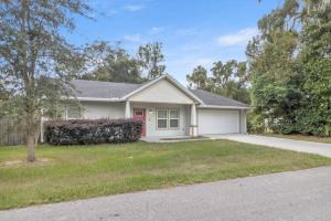 a white house with a garage and a driveway at The Gator Grove Retreat in Gainesville