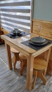 una mesa de madera con dos platos y copas de vino. en Balmaceda Loft, en Puerto Natales