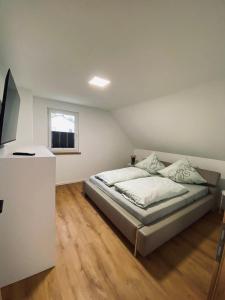 a white bedroom with a bed and a window at Ferienhaus Bleckhausen in Bleckhausen +7 photos