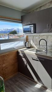 uma cozinha com um lavatório e uma grande janela em Balmaceda Loft em Puerto Natales