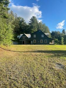 a large black house in the middle of a field at Northern Vermont custom home near Stowe & Smuggs in Johnson