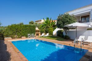 a swimming pool with chairs and an umbrella next to a house at Villa Katerina in Chania Town