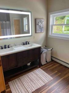 a bathroom with a sink and a mirror and a rug at Northern Vermont custom home near Stowe & Smuggs in Johnson