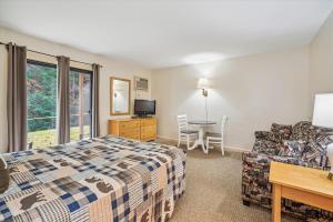 a bedroom with a bed and a couch and a table at Cedarbrook Queen Studio 107 in Killington
