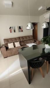 Una sala de estar con un sofá y una mesa de cristal. en Apartamento Horizonte Azul, vista lago, próximo ao shopping, en Palmas