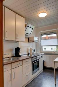 a kitchen with white cabinets and a sink and a window at Gemütliche Wohnung nähe Alsfeld - Parkplatz in Alsfeld