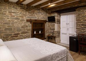1 dormitorio con cama y pared de piedra en Casa Baran, en Sarria