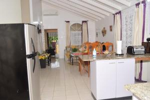 a kitchen with a refrigerator and a living room at Rhyne Park Inn in Montego Bay