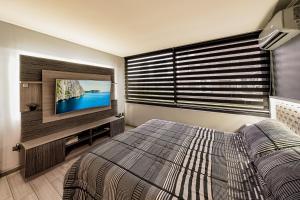 a bedroom with a bed and a flat screen tv at Encomenderos Design Tech Comfort & Location in Santiago