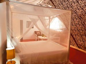 1 dormitorio con cama con dosel en una habitación en Villas Dora and Holly, en Diani Beach