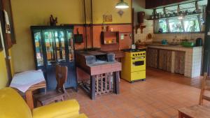 cocina con fogones y horno amarillo en Sítio Kikiô - À Beira Rio em Lumiar en Nova Friburgo