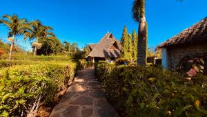 a path leading to a house with a palm tree at Villas Dora and Holly in Diani Beach