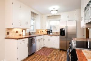 una cucina con armadi bianchi e frigorifero in acciaio inossidabile di Beard Avenue Bungalow! a Minneapolis