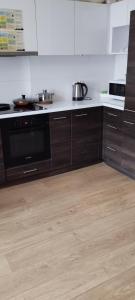 a kitchen with wooden cabinets and a black dishwasher at Hostel ALEX&TSA in Kraków