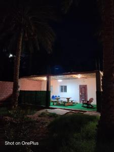 una casa por la noche con una mesa y un banco en le jardin des palmiers Biskra, 