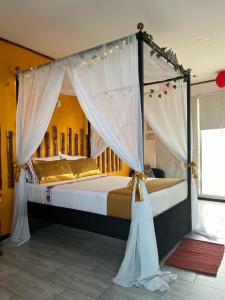 a bedroom with a canopy bed with white curtains at HOTEL PH GIRARDOT in Girardot