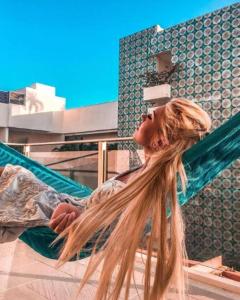 una mujer está sentada en una hamaca con su pelo en Hotel The Palm en Playa del Carmen