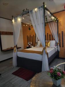 een slaapkamer met een bed met gordijnen en een tafel bij HOTEL PH GIRARDOT in Girardot