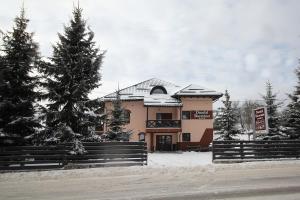 a building with a fence and trees in the snow at Ducatul Bucovinei in Mănăstirea Humorului