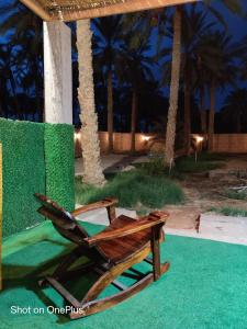 una silla de madera sentada junto a una palmera en le jardin des palmiers Biskra, 