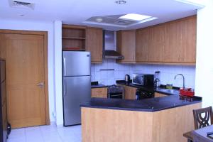 una cocina con nevera de acero inoxidable y armarios de madera en Dreams Hostel en Dubái