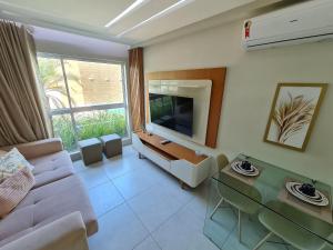 a living room with a couch and a television at Fuja para o Paraíso em Porto de Galinhas! in Porto De Galinhas