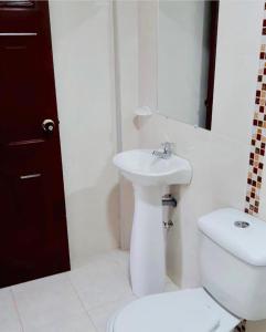 Un baño blanco con inodoro y lavabo. en Buen Vivir Restrepo a 30 minutos Lago Calima, en Restrepo