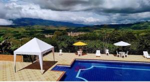 una piscina con sombrillas y sillas en Buen Vivir Restrepo a 30 minutos Lago Calima en Restrepo