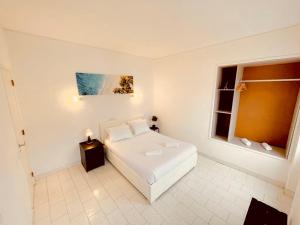1 dormitorio con cama blanca y ventana en Central Atlantic Beach Guesthouse, en Costa da Caparica