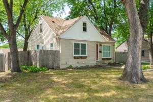 una casa blanca con una valla y árboles en Contempo Cottage, en Minneapolis