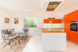 eine Küche mit orangefarbenen Schränken sowie einem Tisch und Stühlen in der Unterkunft L'Atelier 4 stars Luxury, Hot Tub, Pool in Nambsheim