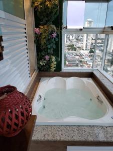 a jacuzzi tub in a bathroom with a window at Banho de Lua - Vaca Brava in Goiânia