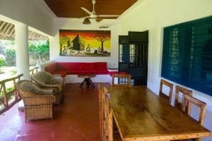 a living room with a wooden table and a red couch at Villas Dora and Holly in Diani Beach