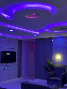 ein Wohnzimmer mit violetten Lichtern an der Decke in der Unterkunft شاليه الفخامه٢ in Ḑubā