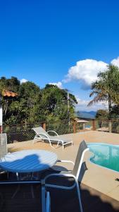 a patio with two chairs and a swimming pool at Pousada Kokopelli in Lavras Novas