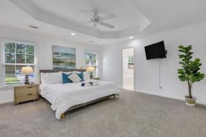 a white bedroom with a bed and a ceiling fan at Savannah 5BR Pool, Jacuzzi, Firepit, Sports, Games in Savannah