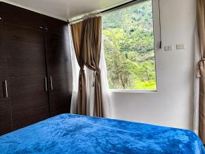 ein Schlafzimmer mit einem blauen Bett und einem Fenster in der Unterkunft CASA VISTA HERMOSA in Baños