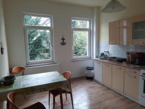 eine Küche mit einem Tisch und 2 Fenstern in der Unterkunft Apartments Wagner in Crimmitschau