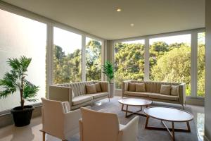 una sala de estar con grandes ventanas, sofás y mesas. en Laghetto Resort Golden Oficial en Gramado