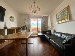 sala de estar con sofá de cuero negro y mesa en L’Attico Sul Fiume center home, en Ascoli Piceno