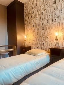 two beds in a room with a wall covered in photographs at LA MARIEFACTURE - Comme un Livre Ouvert in La Petite-Pierre