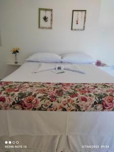 a bed with a floral bedspread on top of it at Pousada Flor do Campo in Icapuí