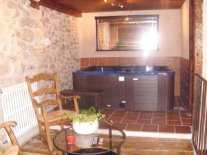 ein Bad mit einer Badewanne, einem Tisch und Stühlen in der Unterkunft Casa Rural con Jacuzzi Taberna del Tio Pedro in Cabañas de Polendos + 1 Foto