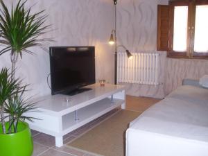 a living room with a tv on a white table at Casa Rural con Jacuzzi Taberna del Tio Pedro in Cabañas de Polendos